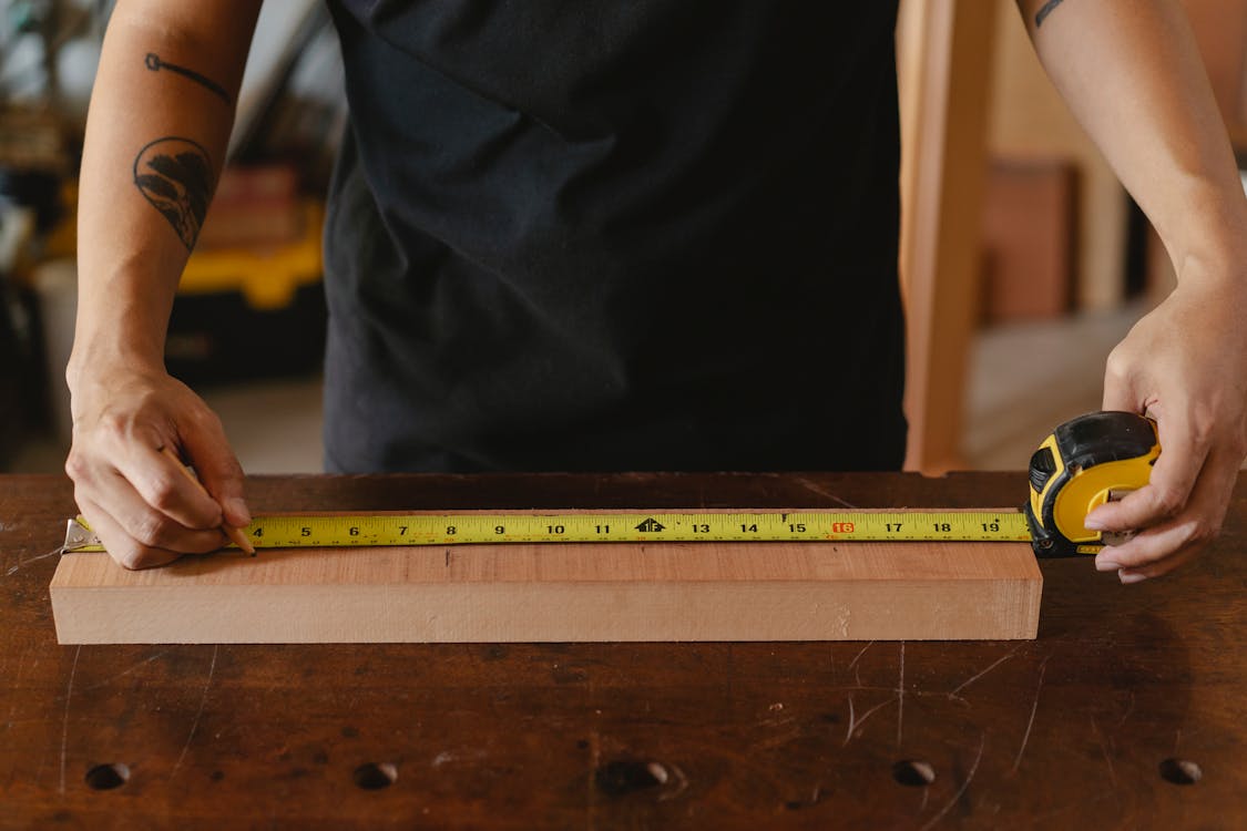 Craftsman measuring wooden board in workshop